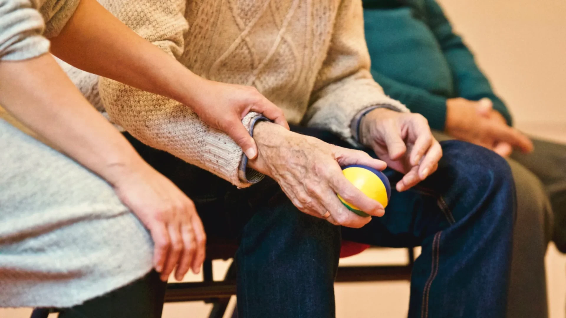 An elderly person holding a yellow ball